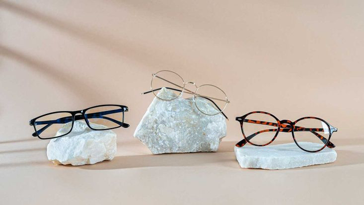 Brillenkollektion für Herren. Brillenverkaufsbanner. Ausverkaufsangebot für Optikgeschäfte. Trendige Brille mit Kunststoff- und Metallrahmen auf Steinen auf beigem Hintergrund