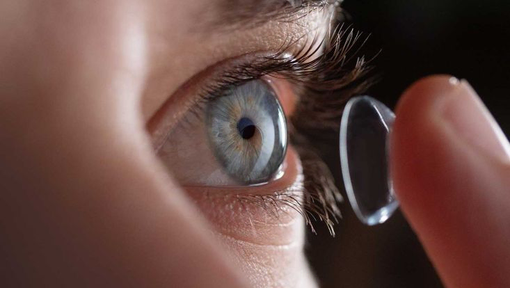 Nahaufnahme eines Mannes, der Kontaktlinsen auf sein blaues Auge setzt. Konzept: Gesundheitsfürsorge, Optik, Hydratation des Auges.