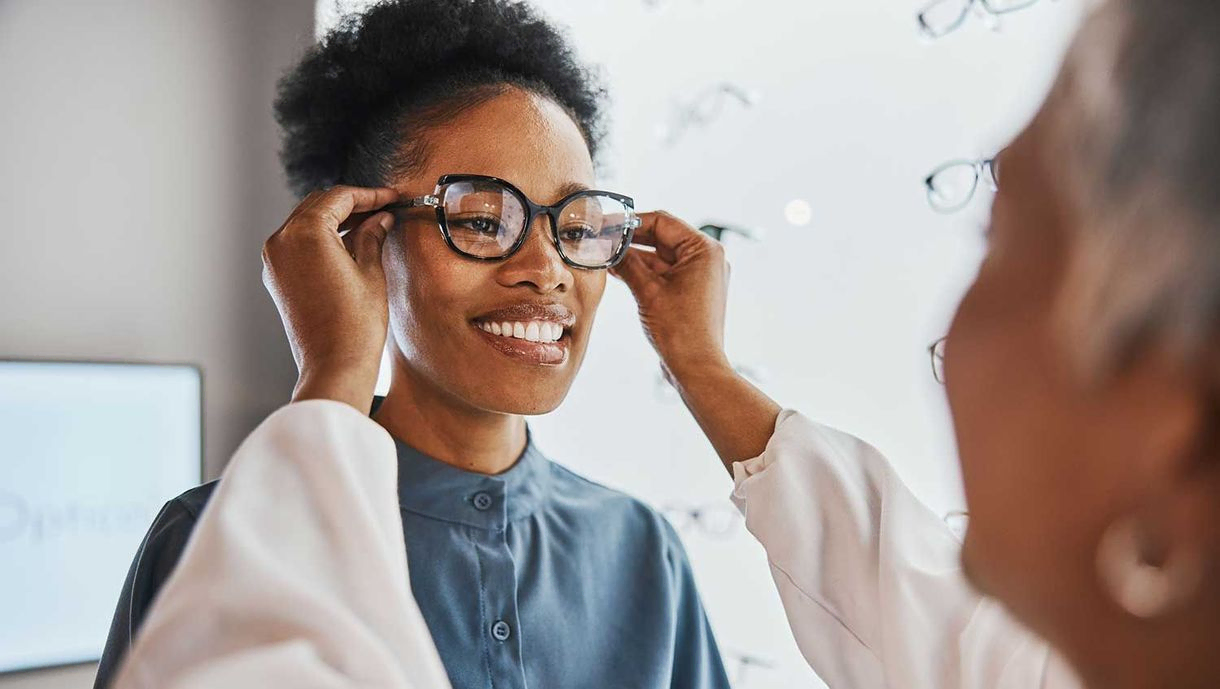 Brillenkontrolle, schwarze Frau und Kunde mit Ladenmitarbeiter und Optiker, die auf die Linse schauen. Augenberatung, Beurteilung des Lächelns und der Brille in einem Rahmengeschäft für Sehtest und Verschreibungsprüfung für die Augen