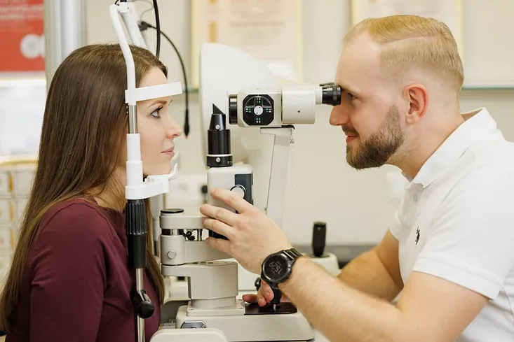 Lächelnde Patientin wartet auf einen Sehtest im Optikergeschäft oder in der Augenklinik