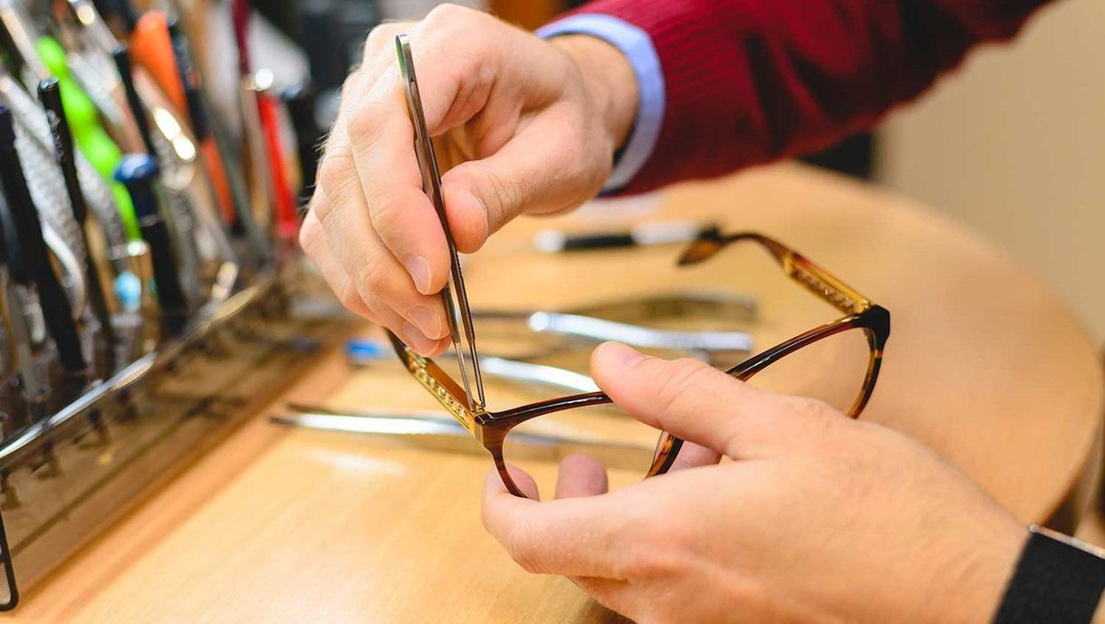 Nahaufnahme männlicher Optikerhände, die eine Brille reparieren