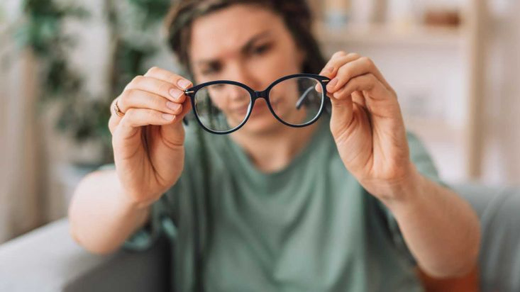 Das Mädchen schaut auf die Brille und sucht nach Schmutz.