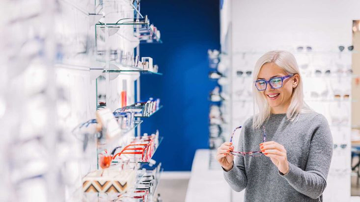 Frau betrachtet Brille im Optikgeschäft